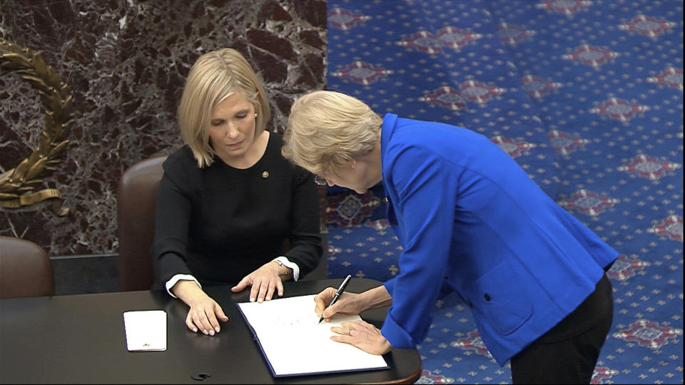 In this image from video, Sen. Elizabeth Warren, D-Mass., signs the oath book after being sworn in for the impeachment trial of President Donald Trump in the Senate at the U.S. Capitol in Washington, Thursday, Jan. 16, 2020. (Senate Television via AP)