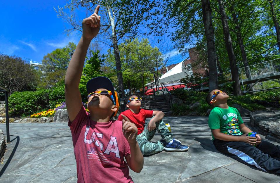 Kayden Day, left, Ayden Day, and Jayde Day of Augusta, Georgia, check out the sun with proper solar eclipse glasses with their father Dion Day at Falls Park 12:45 pm, about an hour before the start of a solar eclipse with viewers in Greenville, S.C. Monday, April 8, 2024. The peak time is estimated 3:08 p.m.