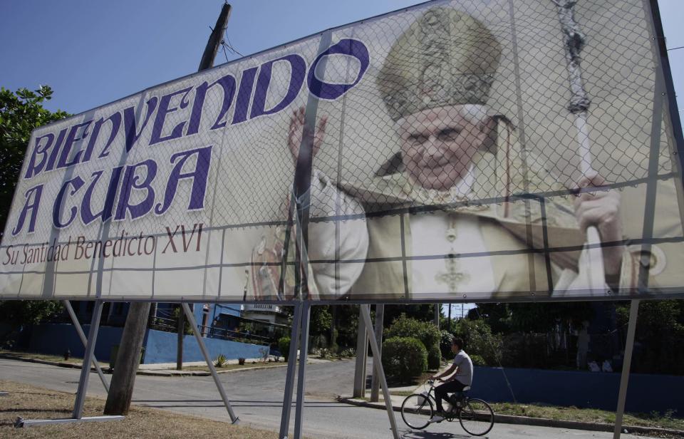 A man rides his bicycle past a billboard welcoming Pope Benedict XVI, just days before his arrival, in Havana, Cuba, Wednesday March 21, 2012. Pope Benedict XVI's trip to Latin America takes him to the region's most Catholic country; Mexico, and then Cuba, where churches are mostly empty and until the 1990s, believers were barred from the Communist Party. (AP Photo/Javier Galeano)