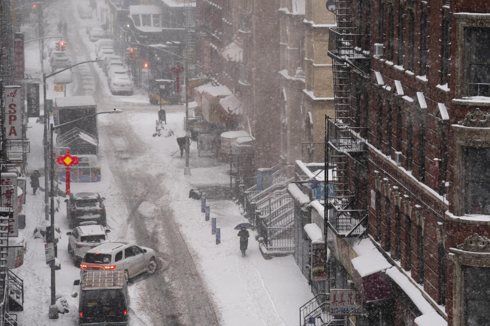 A pedestrian walks down a snow covered sidewalk in the Chinatown nieghborhood of the Manhattan borough of New York, Monday, Feb. 1, 2021. (AP Photo/John Minchillo)