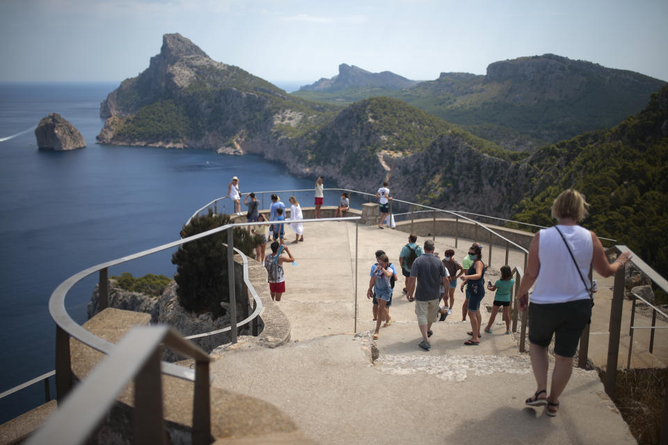 Tourists visit a viewpoint in Pollença, in the Balearic Island of Mallorca, Spain, Tuesday, July 28, 2020. Britain has put Spain back on its unsafe list and announced Saturday that travelers arriving in the U.K. from Spain must now quarantine for 14 days. (AP Photo/Joan Mateu)