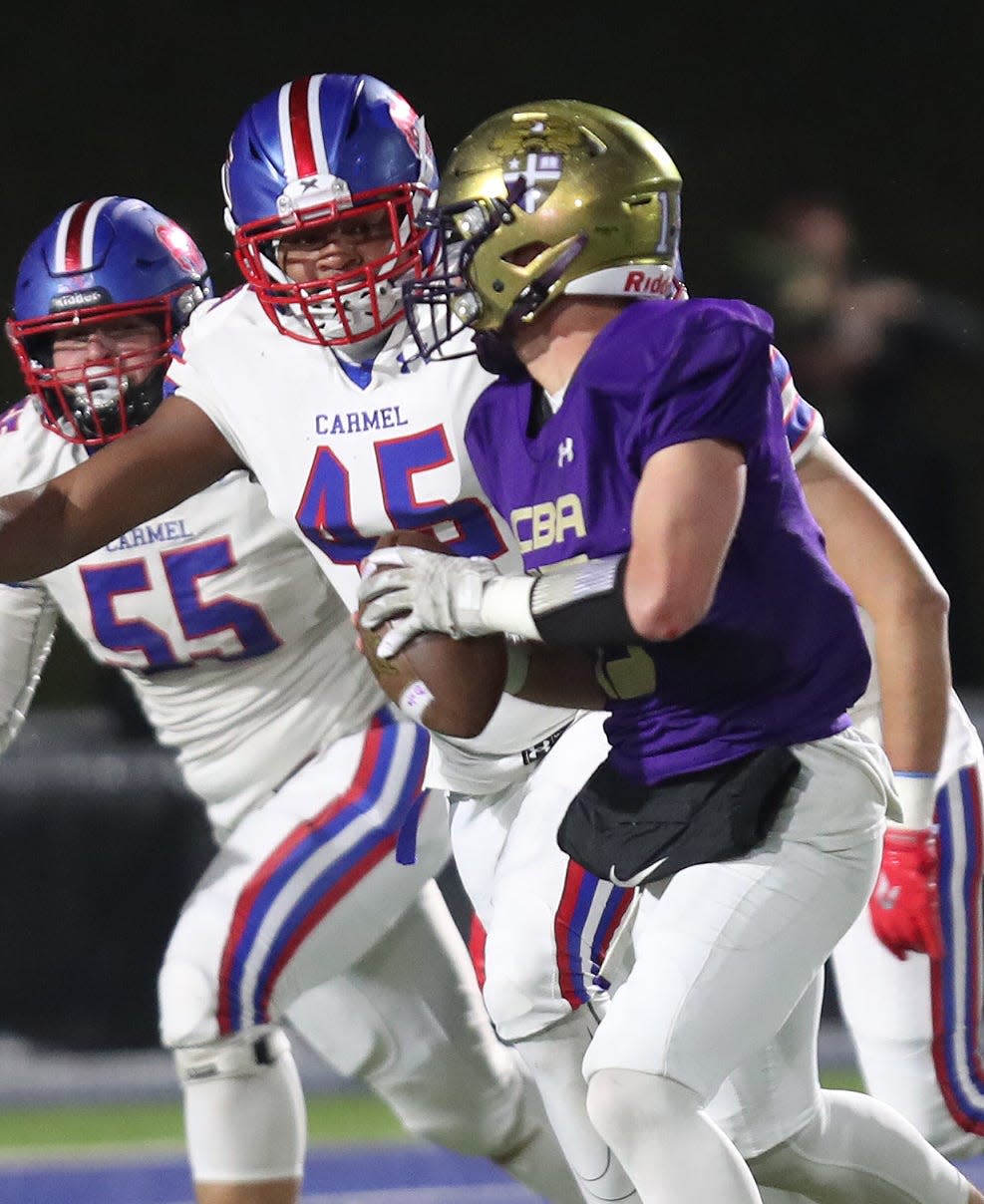 Carmel's Jayden Robles (55) and King Mercer (45) put pressure on Christian Brothers Academy quarterback Jake Iacobaccio (15) during the Class AA state semifinal playoff game at Middletown High School Nov. 25, 2023.