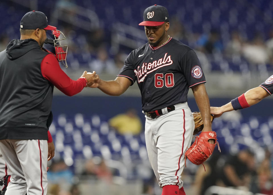Washington Nationals starting pitcher Joan Adon (60) gives up the ball to manager Dave Martinez during the fourth inning of a baseball game against the Miami Marlins, Tuesday, June 7, 2022, in Miami. (AP Photo/Marta Lavandier)