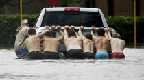 <p>People push a stalled pickup to through a flooded street in Houston, after Tropical Storm Harvey dumped heavy rains Sunday, Aug. 27, 2017. (Photo: Charlie Riedel/AP) </p>