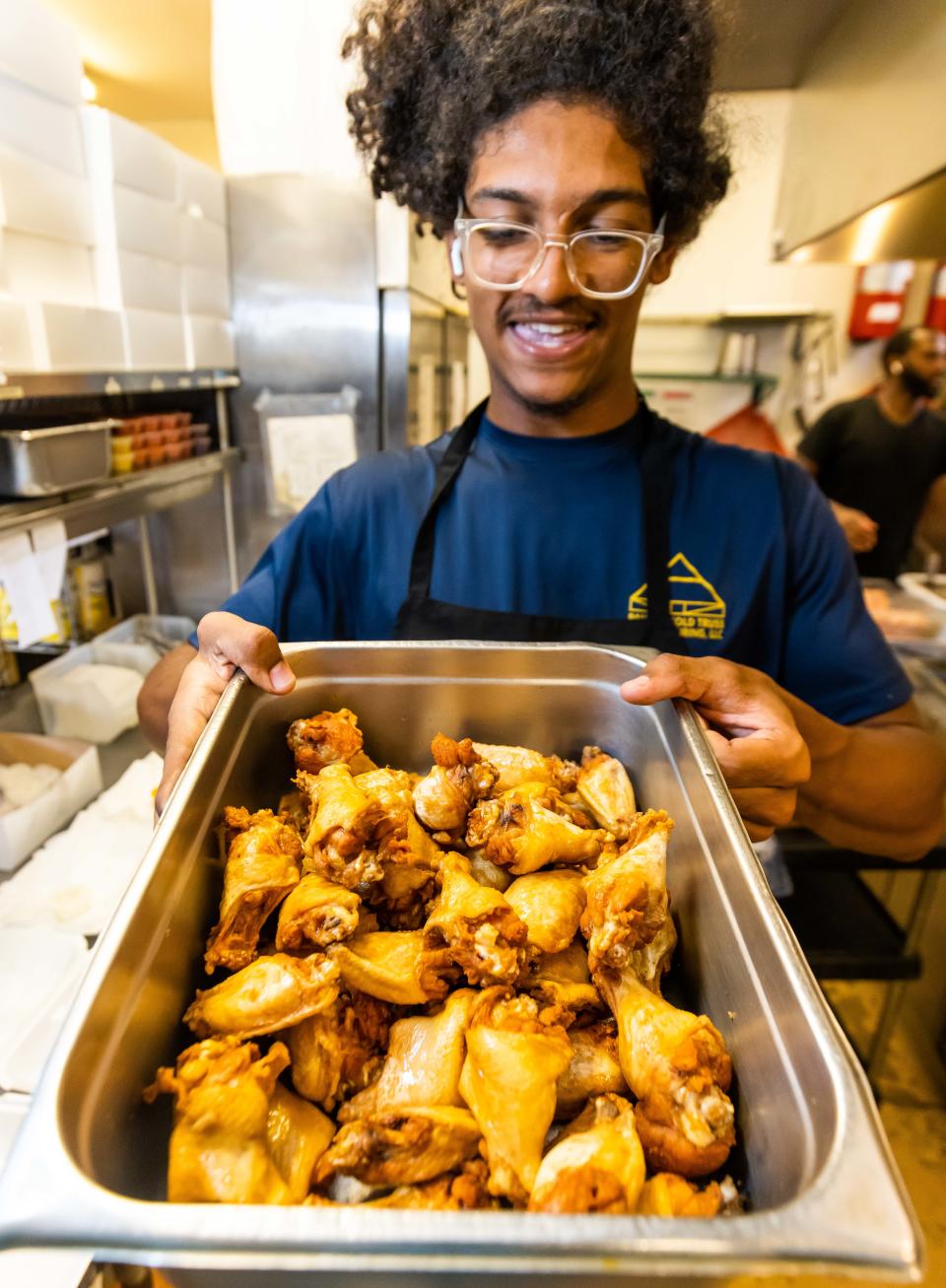 Crunchies & Munchies employee Michael Scott carries a full tray of freshly deep fried wings on July 14.