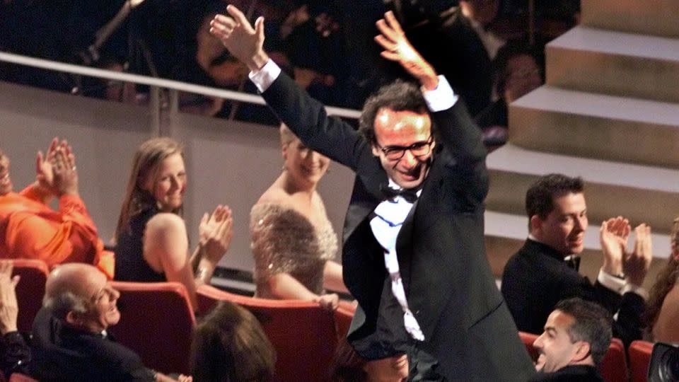 Director and actor Roberto Benigni jumps on the back of some chairs in excitement after winning the Oscar for best foreign language film for "Life is Beautiful" at the Oscars in 1999. - Eric Draper/AP