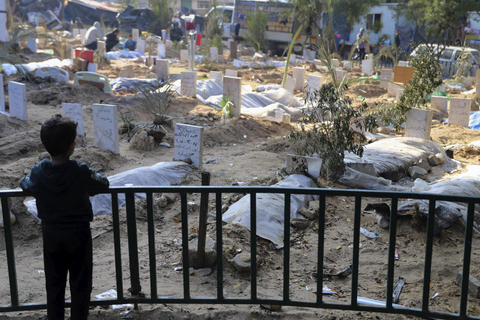 FILE - A Palestinian child looks at the graves of people killed in the Israeli bombardment of the Gaza Strip and buried inside the Shifa Hospital grounds in Gaza City, Sunday, Dec. 31, 2023. South Africa has launched a case at the United Nations' top court alleging that Israel's military campaign in Gaza amounts to genocide. The filing and Israel's decision to defend itself at the International Court of Justice sets up a high-stakes showdown in the before a bench of the court's black-robed judges in the wood-panelled Great Hall of Justice. (AP Photo/Mohammed Hajjar, File)