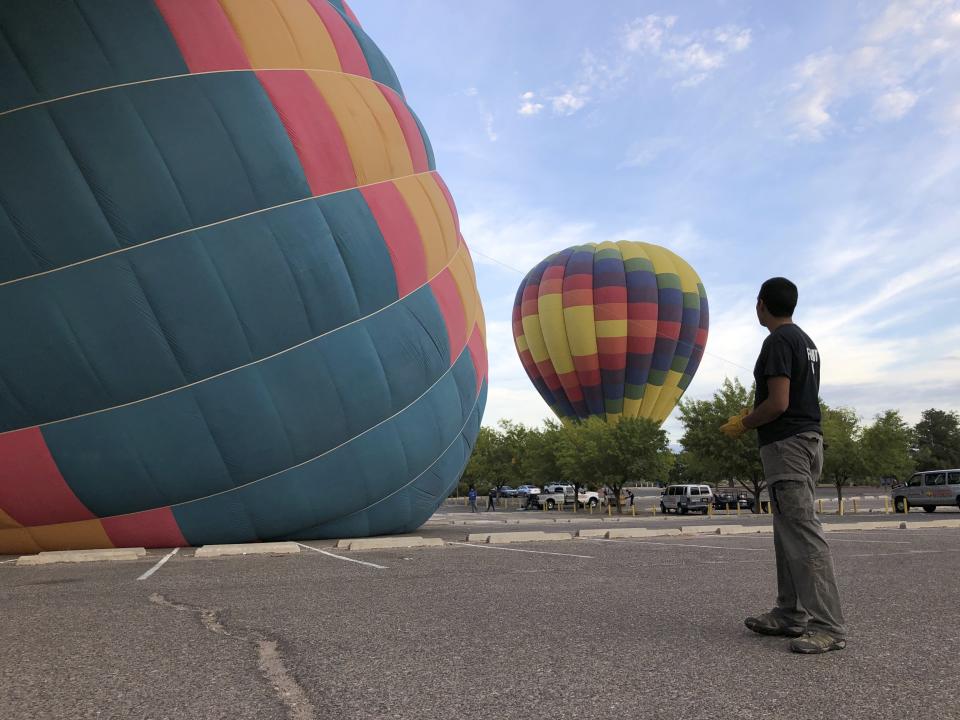 Elijah Sanchez monitors the inflation of hot air balloons operated by Rainbow Ryders in Albuquerque, N.M., on Tuesday, Oct. 1, 2019. Sanchez, 20, will be among the youngest pilots to launch as part of this year's Albuquerque International Balloon Fiesta. The nine-day event is expected to draw several hundred thousand spectators and hundreds of balloonists from around the world. It will kick off Oct. 5 with a mass ascension. (AP Photo/Susan Montoya Bryan)