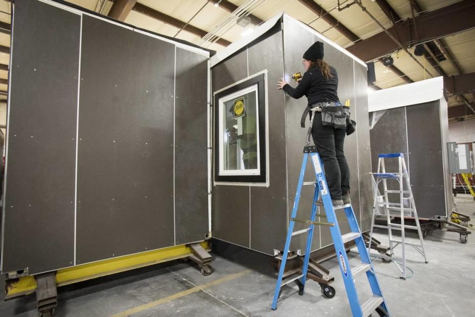 Laura Mock installs siding on an IndieDwell shipping-container home at the company's former Caldwell factory. 