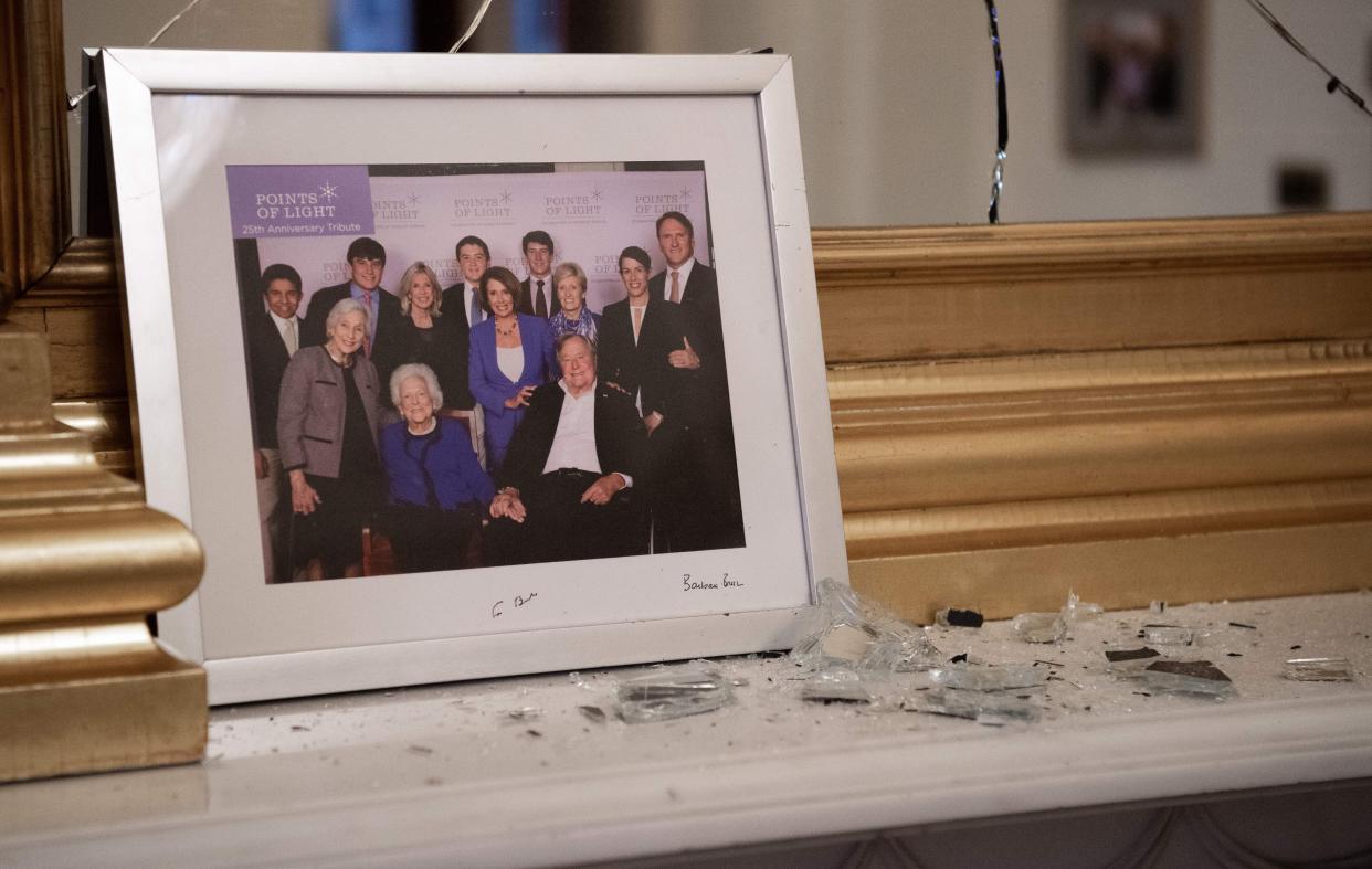 Broken glass litters a mantle in Pelosi's offices before a photo of the speaker and the late President George H.W. Bush. (Photo: SAUL LOEB via Getty Images)