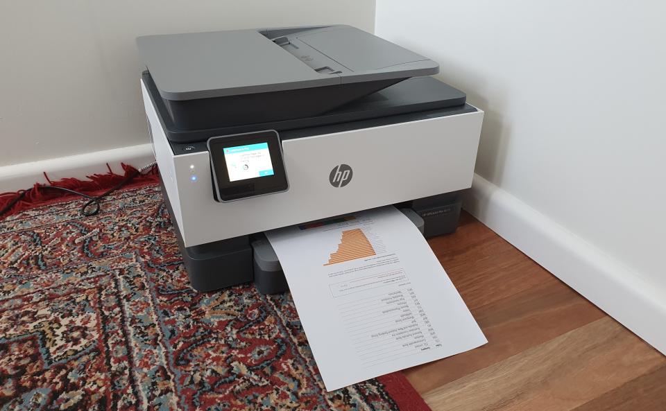 HP OfficeJet Pro 9010 printer with paper coming out of it.