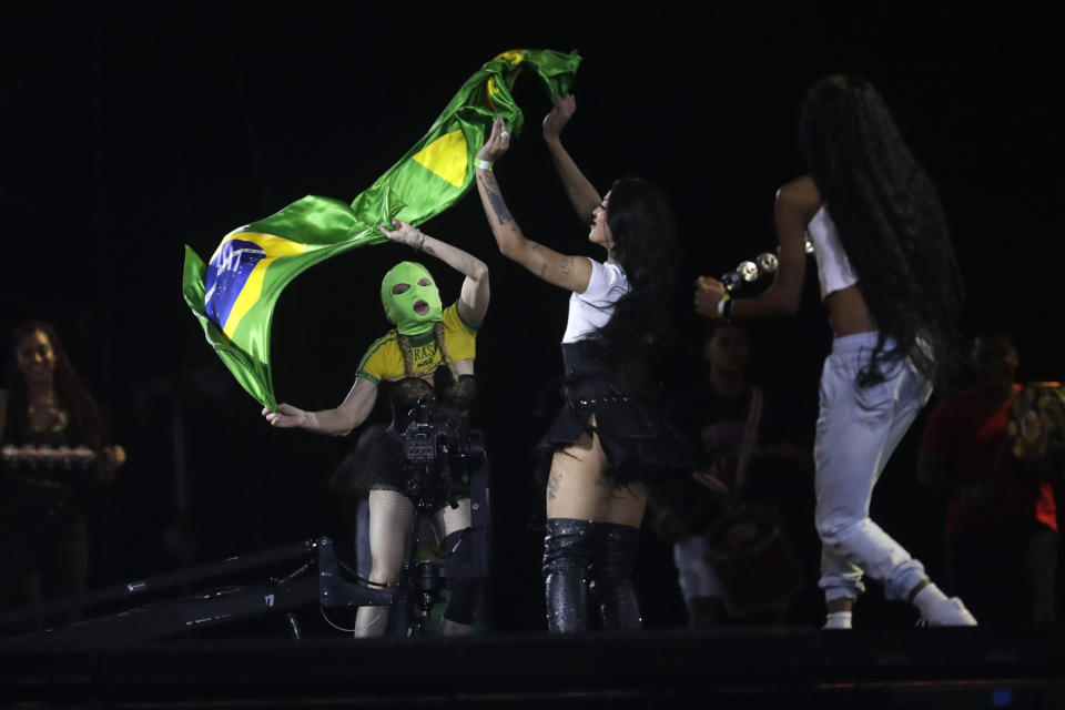 Madonna, left, wearing a mask, and Brazilian singer Pabllo Vittar wave a national flag during a rehearsal of The Celebration Tour, in Rio de Janeiro, Brazil, Friday, May 3, 2024. Madonna will conclude her tour on Saturday with a free concert at Copacabana Beach. (AP Photo/Bruna Prado)