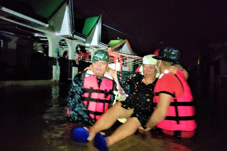 In this photo provided by the Philippine Coast Guard, rescuers carry a woman following the sudden rise in floodwaters as Typhoon Goni hits Batangas province, south of Manila, Philippines, Sunday, Nov. 1, 2020. The super typhoon blew into the eastern Philippines with disastrous force Sunday. (Philippine Coast Guard via AP)