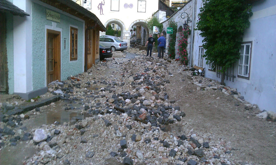 In this picture provided by Hallstatt.net residents look at the flood damage in the village of Hallstatt, Austria, Wednesday, June 19, 2013. A flash flood unleashed by a major thunder storm has inundated the village, which has been awarded special status by the U.N. because of its unique beauty. Wednesday’s storm turned the placid village creek into a raging torrent that flooded the village square, tearing up cobble stones in its wake. Houses and a hotel are partially under water. (AP Photo/Hallstatt.net, Werner Krauss)