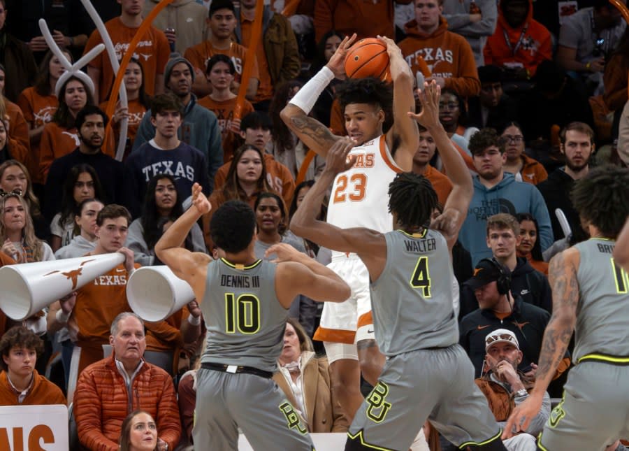 Texas forward Dillon Mitchell (23) rebounds the ball against Baylor guard Rayj Dennis (10) and guard Ja’Koke Walter (4) during the first half of an NCAA college basketball game, Saturday, Jan. 20, 2024, in Austin, Texas. (AP Photo/Michael Thomas)