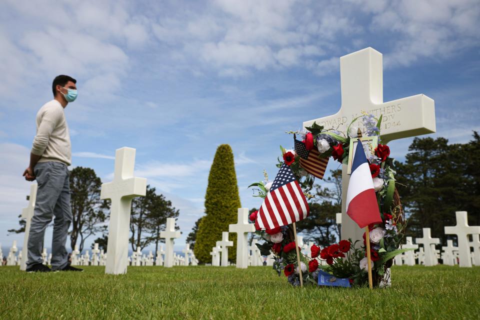 A man stands next to a headstone of a World War II soldier during a ceremony in US cemetery of Colleville-sur-Mer, Normandy on June, 6 2021. Several ceremonies took place that day to commemorate the 77th anniversary of D-Day, which led to the liberation of France and Europe from the German occupation.