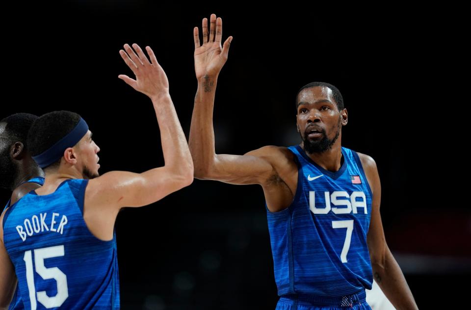 United States' Kevin Durant (7), right, celebrates with teammate Devin Booker (15) after a dunk during men's basketball quarterfinal game at the 2020 Summer Olympics, Tuesday, Aug. 3, 2021, in Saitama, Japan. (AP Photo/Charlie Neibergall).