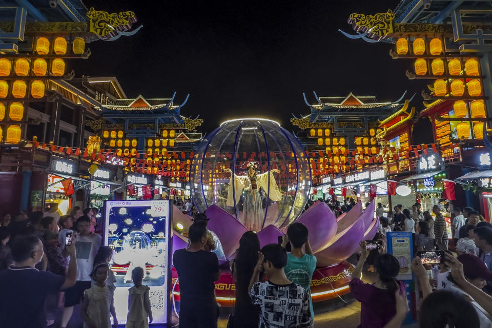 Visitors watch an artist perform in a new night market during a weeklong national holiday in Nanning in south China's Guangxi Zhuang Autonomous Region on Sept. 30, 2023. Tourism in China bounced back to pre-pandemic levels during a recent eight-day national holiday, giving a temporary boost to the nation's flagging economy. (Chinatopix via AP)