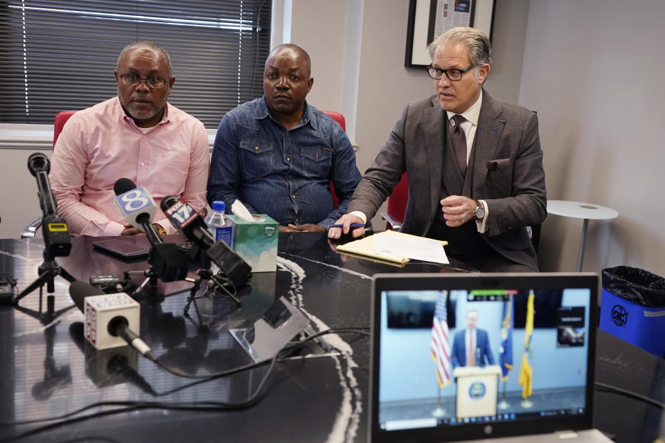 From left, interpreter Israel Siku, Peter Lyoya, and attorney Ven Johnson watch, Thursday, June 9, 2022, in Detroit as Kent County Prosecutor Chris Becker explains his decision to charge Grand Rapids police Officer Christopher Schurr with second-degree murder during a press conference at the Michigan State Police sixth district headquarters in Walker. Schurr fatally shot Black motorist Patrick Lyoya on April 4. (AP Photo/Carlos Osorio)