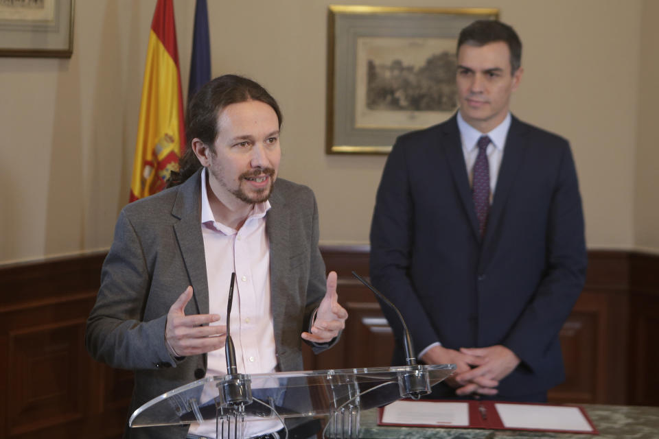 Podemos party leader Pablo Iglesias speaks as Spain's caretaker Prime Minister Pedro Sanchez looks on after signing an agreement at the parliament in Madrid, Spain, Tuesday, Nov. 12, 2019. The leaders of Spain's Socialist party and the left-wing United We Can (Podemos) party say they have reached a preliminary agreement toward forming a coalition government. But the deal announced Tuesday won't provide enough votes in parliament for the Socialists, who won a general election, to take office without the support of other parties. (AP Photo/Paul White)