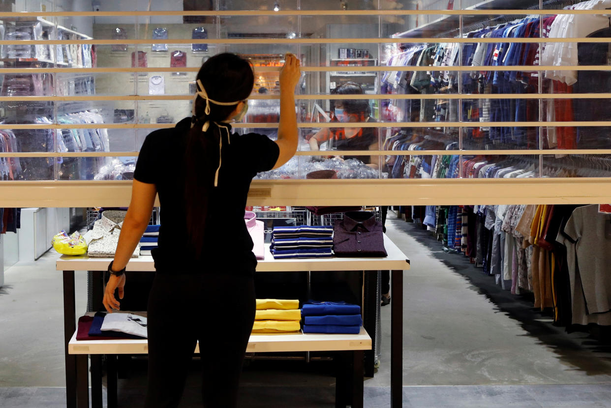 A retail assistant cleans the shop shutter as a shop is prepares to be opened in Singapore as the city state reopens the economy amid the coronavirus disease (COVID-19) outbreak, June 19, 2020.  REUTERS/Edgar Su