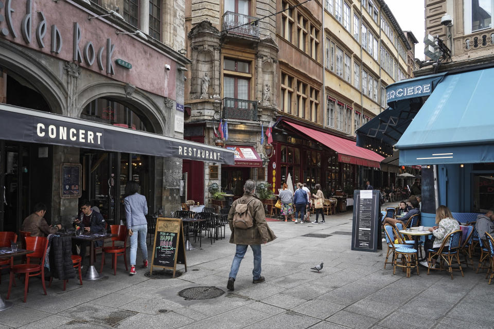 A man walks by restaurants in Lyon, central France, Tuesday, July 13, 2021. Nearly 1 million people in France made vaccine appointments in a single day, as the president cranked up pressure on everyone to get vaccinated to save summer vacation and the French economy. (AP Photo/Laurent Cipriani)