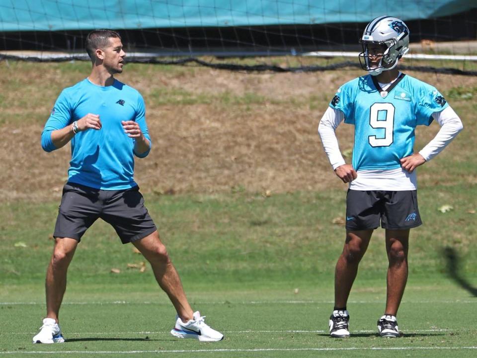 Carolina Panthers head coach Dave Canales, left, demonstrates dropping back with the ball to quarterback Bryce Young, right, during the team’s voluntary minicamp practice on Tuesday, April 23, 2024.