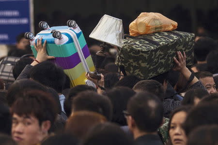 People carry their belongings toward trains at the main railway station in Guangzhou, Guangdong province, China, January 31, 2016, as travel for the annual Chinese Lunar New Year and Spring Festival holidays continues. REUTERS/Alex Lee