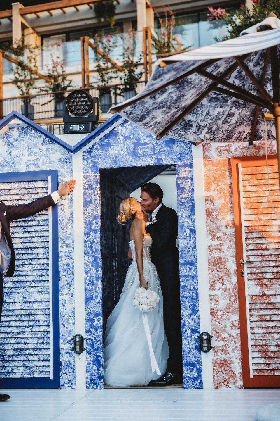 A bride and groom kiss in a doorway.