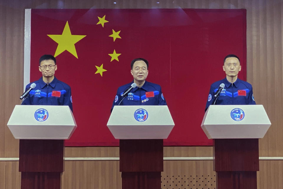 Chinese astronauts for the upcoming Shenzhou-16 mission from left, Gui Haichao, Jing Haipeng and Zhu Yangzhu behind glass meet the reporters at a press conference at the Jiuquan Satellite Launch Center ahead of the launch mission from Jiuquan in northwestern China, Monday, May 29, 2023. China's space program plans to land astronauts on the moon before 2030, a top official with the country's space program said Monday. (AP Photo/Mark Schiefelbein)