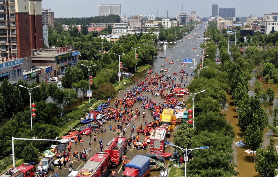 Rescuers evacuate people from a flooded area in Weihui in central China's Henan Province, Monday, July 26, 2021. Residents laid flowers on Tuesday at the entrance of a subway station where more than a dozen people died after a record-breaking downpour flooded large swaths of Henan province in central China. (Chinatopix via AP)