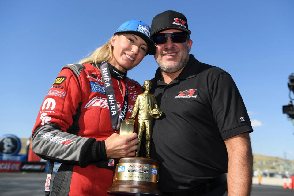 In this 2022 image provided by the NHRA, Leah Pruett and Tony Stewart celebrate Pruett’s Top Fuel win in Denver. Pruett will step away from the NHRA drag racing series in 2024 to focus on starting a family with Tony Stewart. Her NASCAR Hall of Famer husband will replace her next season in the Top Fuel dragster that Pruett drove to a career-best third-place finish in the NHRA standings this year. Pruett and Stewart married just over two years ago. (NHRA via AP)