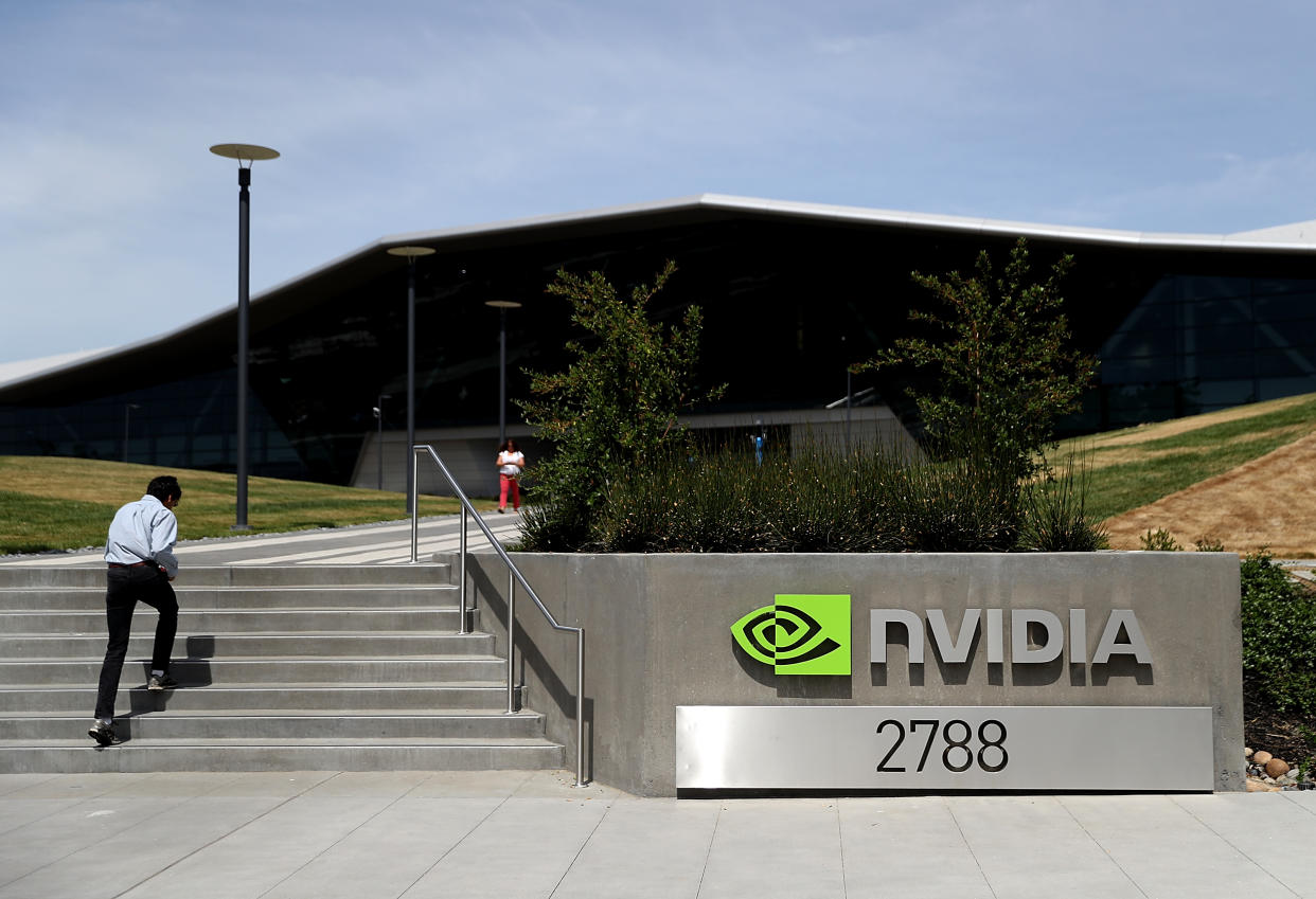 A man passes a Nvidia sign while walking up stairs in front of the Nvidia headquarters.