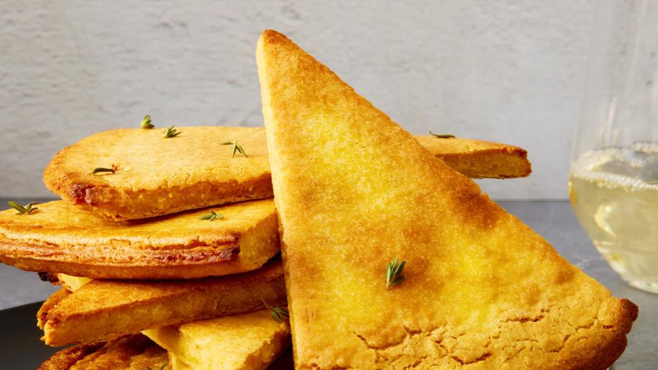 a golden brown mediterranean chickpea flatbread in a cast iron skillet with crispy edges and fresh herbs sprinkled on top