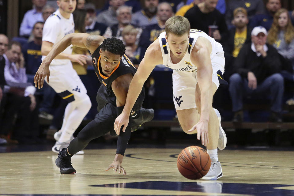 Oklahoma State guard Avery Anderson III (0) and West Virginia guard Sean McNeil (22) scramble for the ball during the first half of an NCAA college basketball game Tuesday, Feb. 18, 2020, in Morgantown, W.Va. (AP Photo/Kathleen Batten)