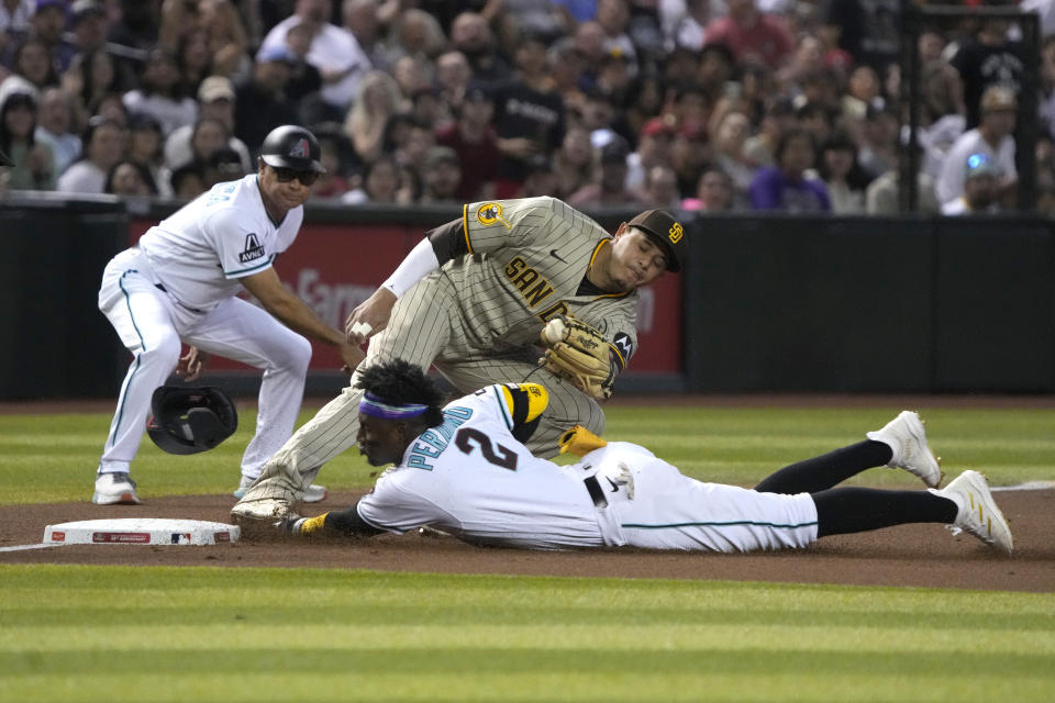 Arizona Diamondbacks' Geraldo Perdomo (2) dives into thirdbase after hitting a triple under the tag of San Diego Padres third baseman Manny Machado in the second inning during a baseball game, Thursday, April 20, 2023, in Phoenix. (AP Photo/Rick Scuteri)