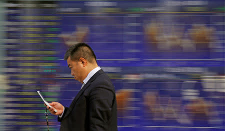 A man walks past an electronic stock quotation board outside a brokerage in Tokyo, Japan, February 9, 2018. REUTERS/Toru Hanai