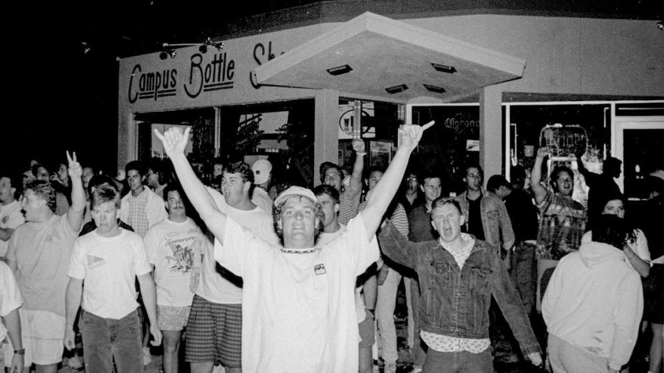 A group of youths gathers at Campus Bottle Shoppe, where police were called after violence erupted on the first night of Poly Royal in 1990.