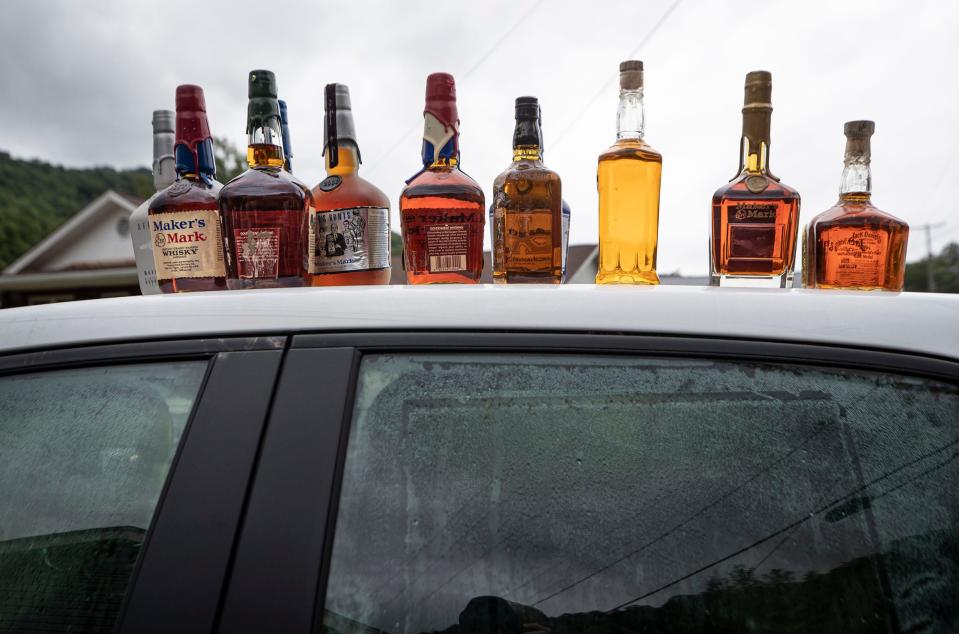 John Eric Wright's collection of bourbon sat on the roof of a car at his home in the Upper Bottoms area of Letcher County, Kentucky after flooding ripped through low lying areas in the region. July 29, 2022