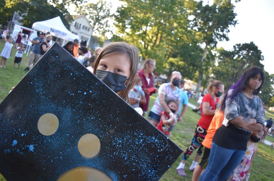 Eight-year-old Ava Medeiros shows off her painting at Summer Evenings in the Park held at Ruggles Park on July 28, 2021. Presented by the city of Fall River and Narrows Center for the Arts, the event takes place every Wednesday night in July and August, from 5:30 to 8 p.m. at four different city parks, featuring live music, arts and crafts, food and more.