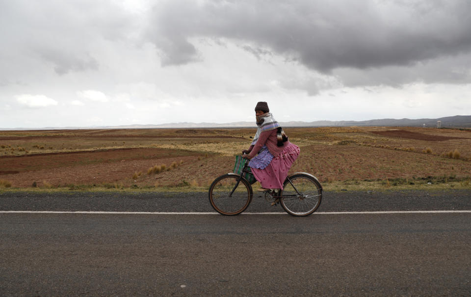 Una mujer monta una bicicleta mientras se dirige a un colegio electoral durante las elecciones generales en el municipio de Guaqui, Bolivia, el domingo 18 de octubre de 2020 (AP Foto/Juan Karita)