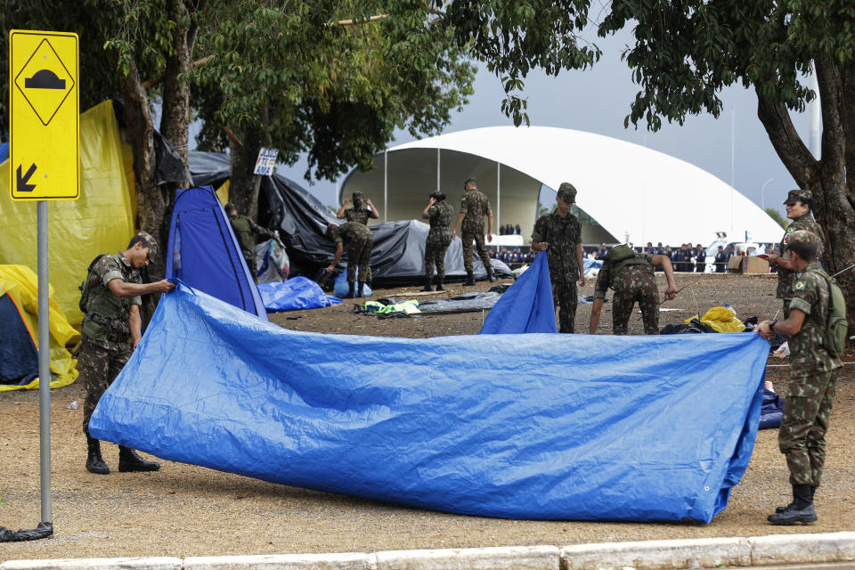 Soldiers help clear out an encampment set up by supporters of former Brazilian President Jair Bolsonaro outside army headquarters in Brasilia, Brazil, Monday, Jan. 9, 2023, the day after Bolsonaro supporters stormed government buildings in the capital. (AP Photo/Gustavo Moreno)