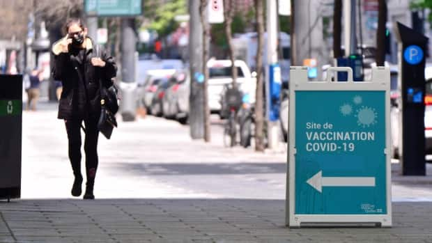 A woman walks by a sign advertising for COVID-19 vaccines in Montreal on May 14.   