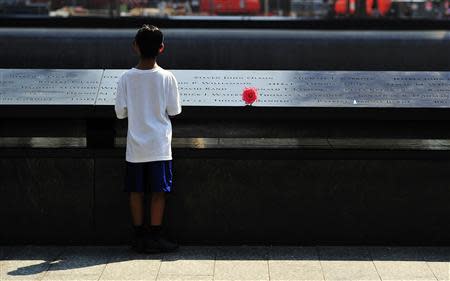 A boy looks at names on the South reflecting pool at the 9/11 Memorial during ceremonies marking the 12th anniversary of the 9/11 attacks on the World Trade Center in New York, September 11, 2013. REUTERS/Stan Honda/Pool