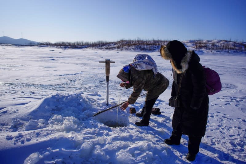 Fisherman fishes on a frozen river in Tongjiang