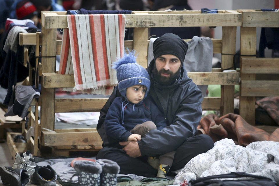 A man and his child rest inside a logistics center at the checkpoint "Kuznitsa" at the Belarus-Poland border near Grodno, Belarus, Sunday, Nov. 28, 2021. The West has accused Belarusian President Alexander Lukashenko of luring thousands of migrants to Belarus with the promise of help to get to Western Europe to use them as pawns to destabilize the 27-nation European Union in retaliation for its sanctions on his authoritarian government. Belarus denies engineering the crisis. (Leonid Shcheglov/BelTA via AP)
