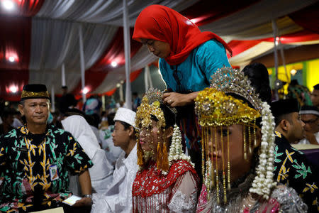 A bride has her headdress adjusted while taking part in a mass wedding organised by the city government as part of New Year's Eve celebrations in Jakarta, Indonesia, December 31, 2017. REUTERS/Darren Whiteside