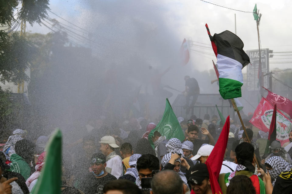 Riot police spray protesters with a water cannon during a demonstration in solidarity with the Palestinian people in Gaza, near the U.S. embassy in Aukar, a northern suburb of Beirut, Lebanon, Wednesday, Oct. 18, 2023. (AP Photo/Bilal Hussein)