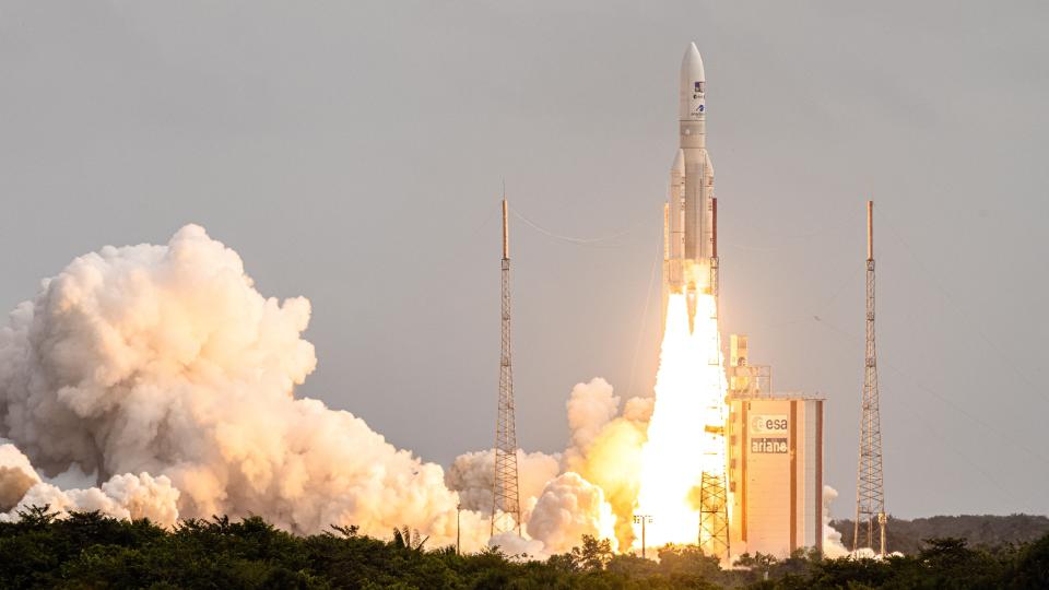 JUICE mission launch shows the Ariane 5 rocket lifting off from the launch pad with billowing clouds beneath.