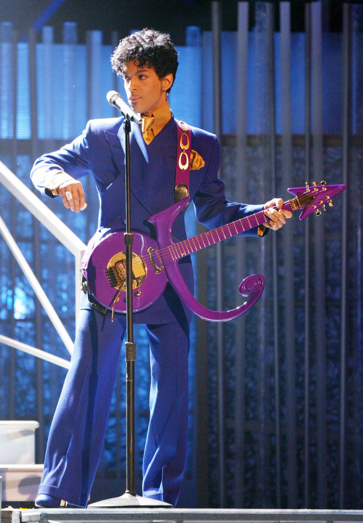 "Purple Rain" singer holding a guitar in the shape of the combination of the man and woman symbols